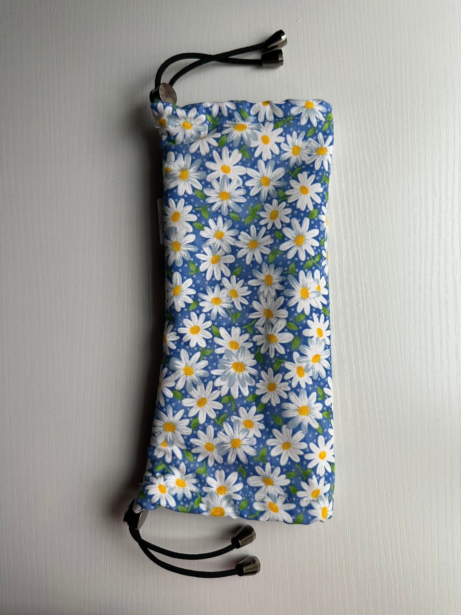 Sling Safe drawstring washing cover for ring slings, shown in the pattern Bluebell. Bluebell is a daisy floral with white flowers and a blue background. 