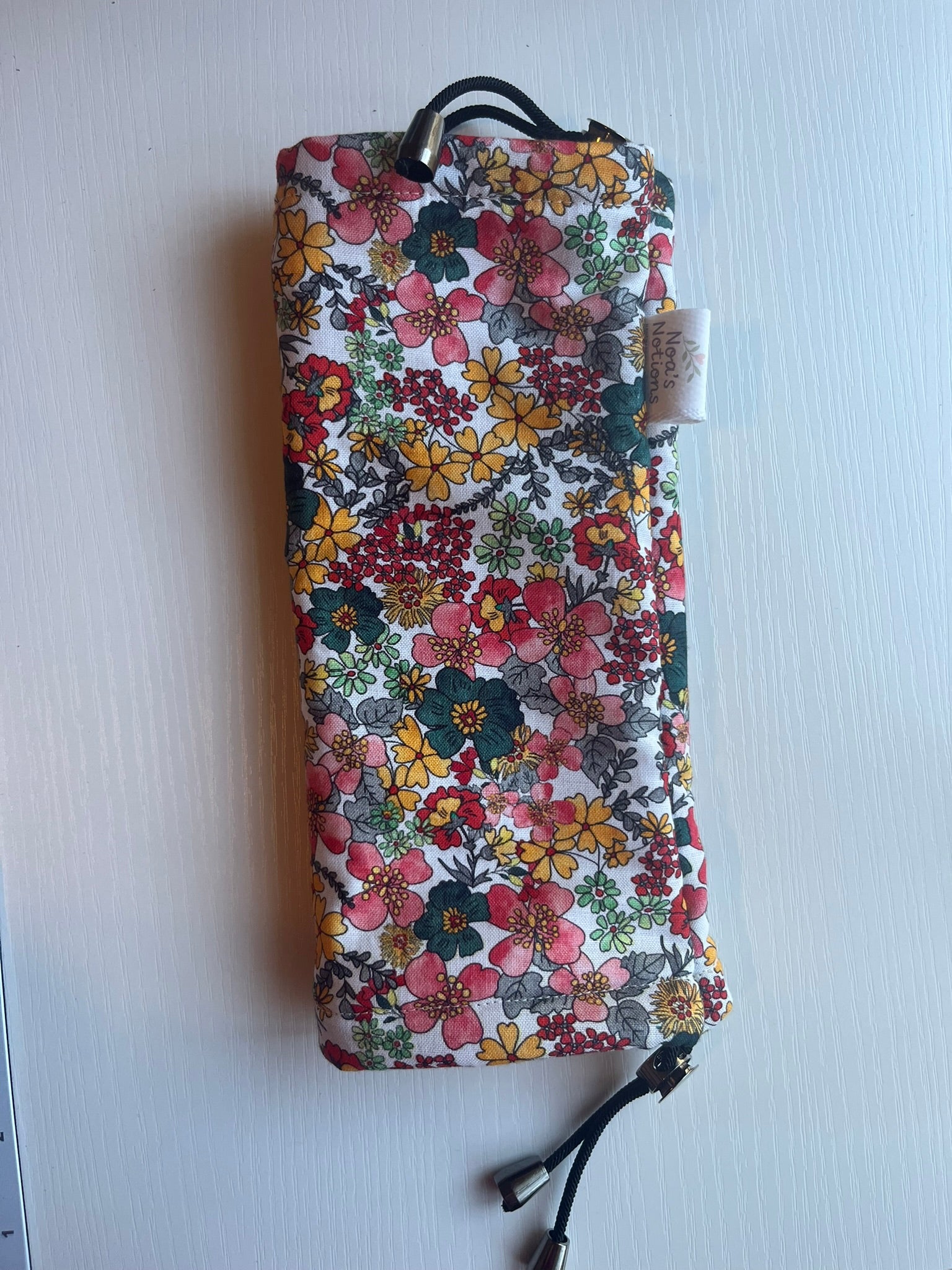 Sling Safe drawstring washing cover for ring slings, shown in the pattern Floral Fire. Floral Fire is a red, yellow, green and teal floral.