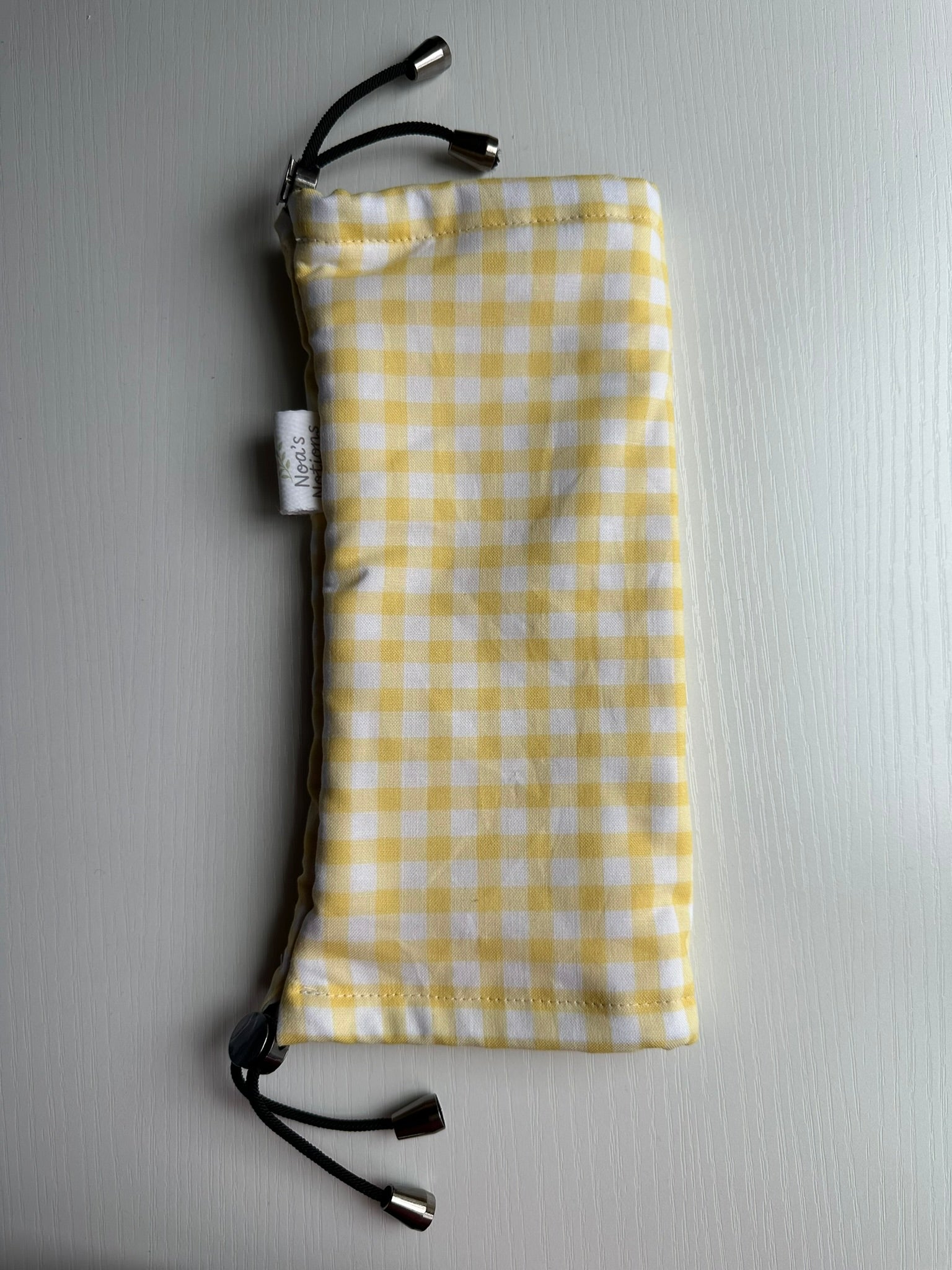 Sling Safe drawstring washing cover for ring slings, shown in the pattern Honey. Honey is a white and yellow gingham.