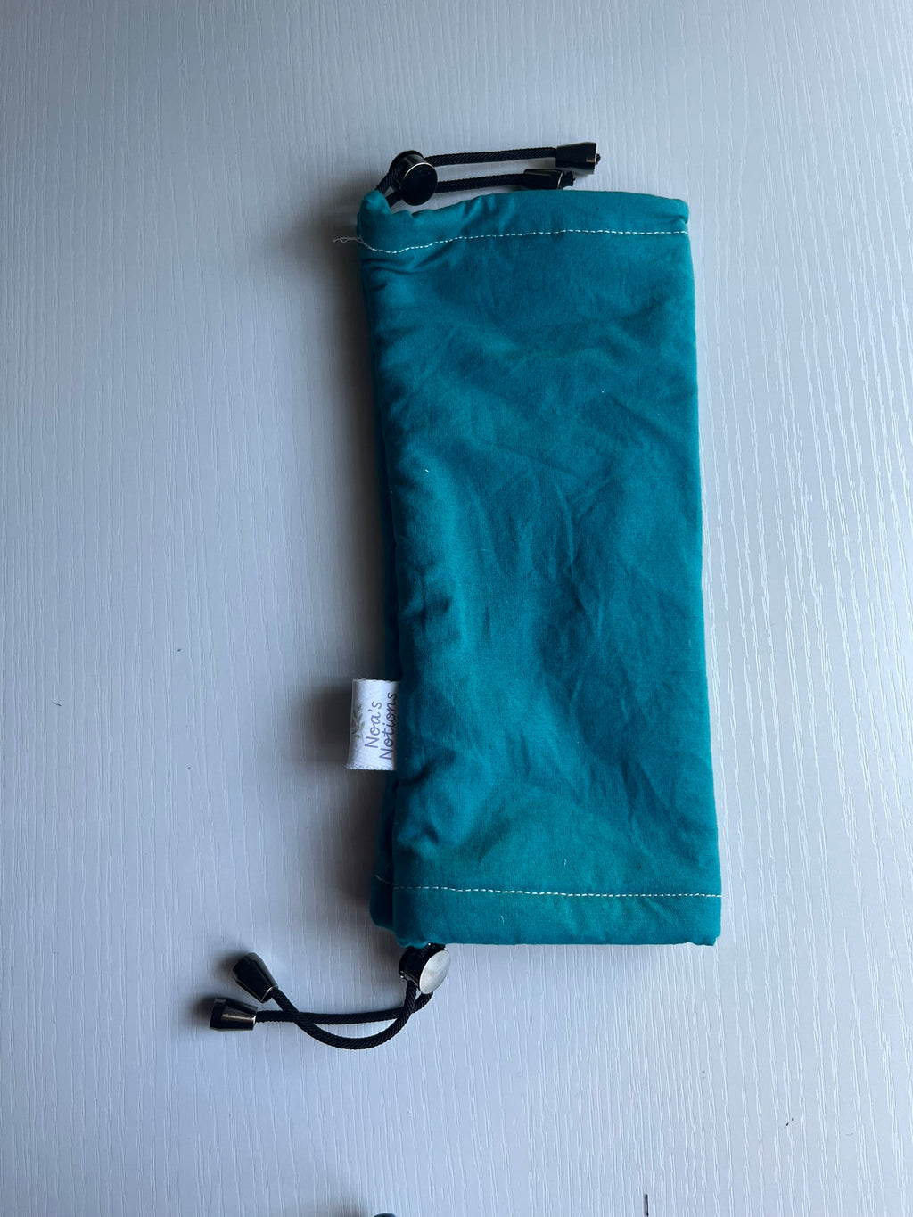 Teal drawstring bag on a light gray background