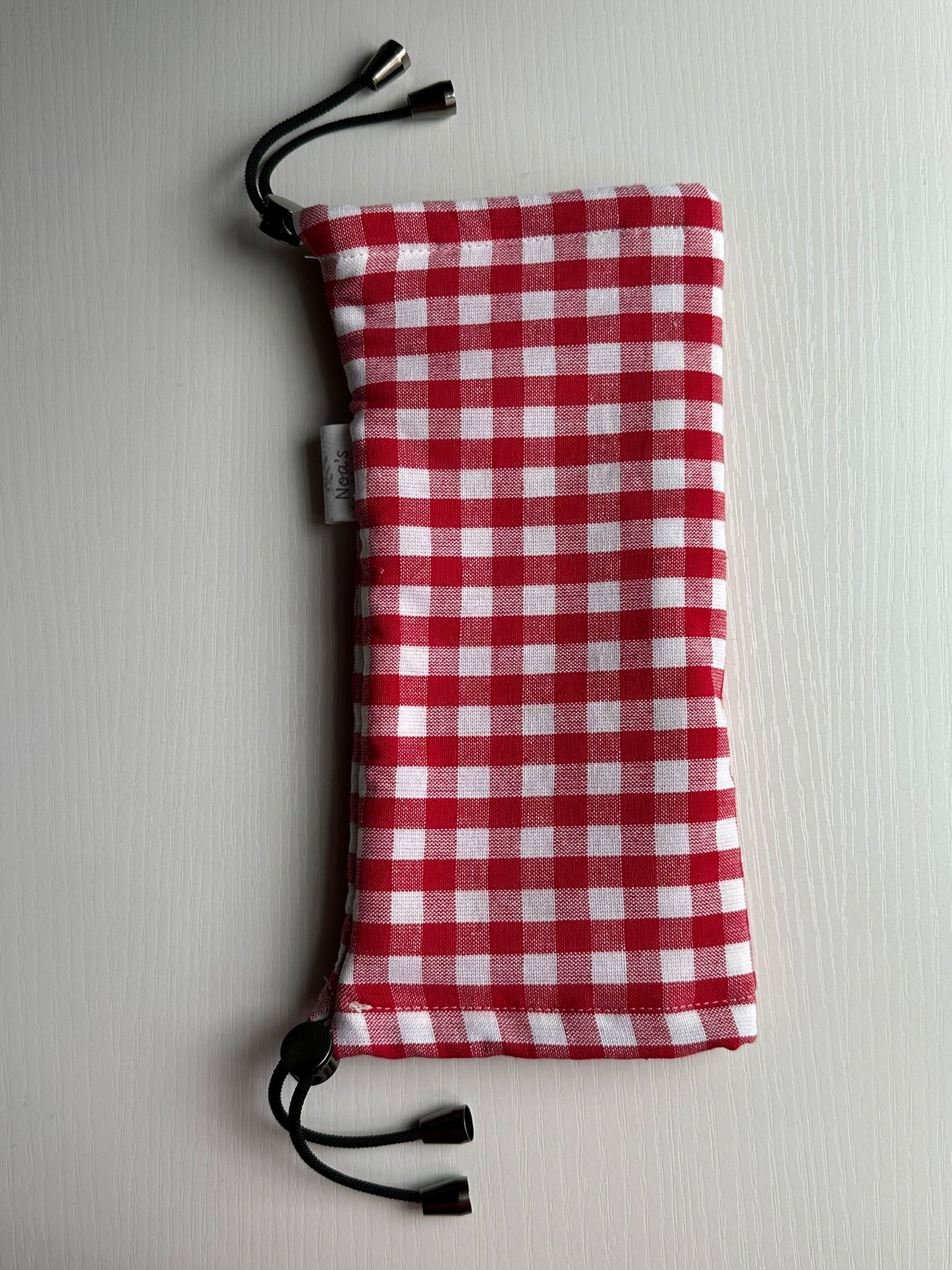 Sling Safe drawstring washing cover for ring slings, shown in "Parton" fabric. Parton is a red and white gingham