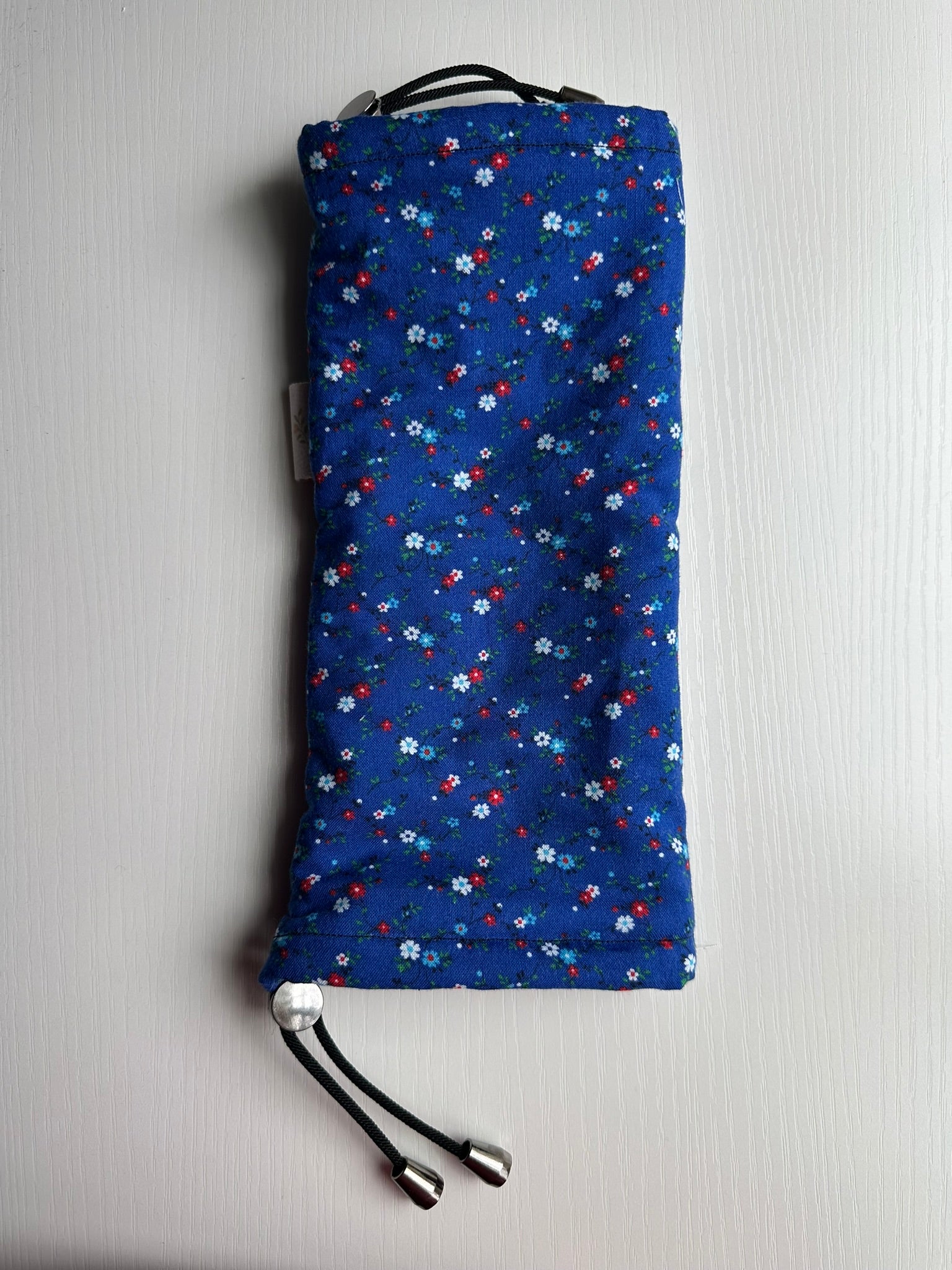 Sling Safe drawstring washing cover for ring slings, shown in the pattern Red, White and Bloom. Red , White and Bloom is a blue background with small red, white and blue flowers throughout.