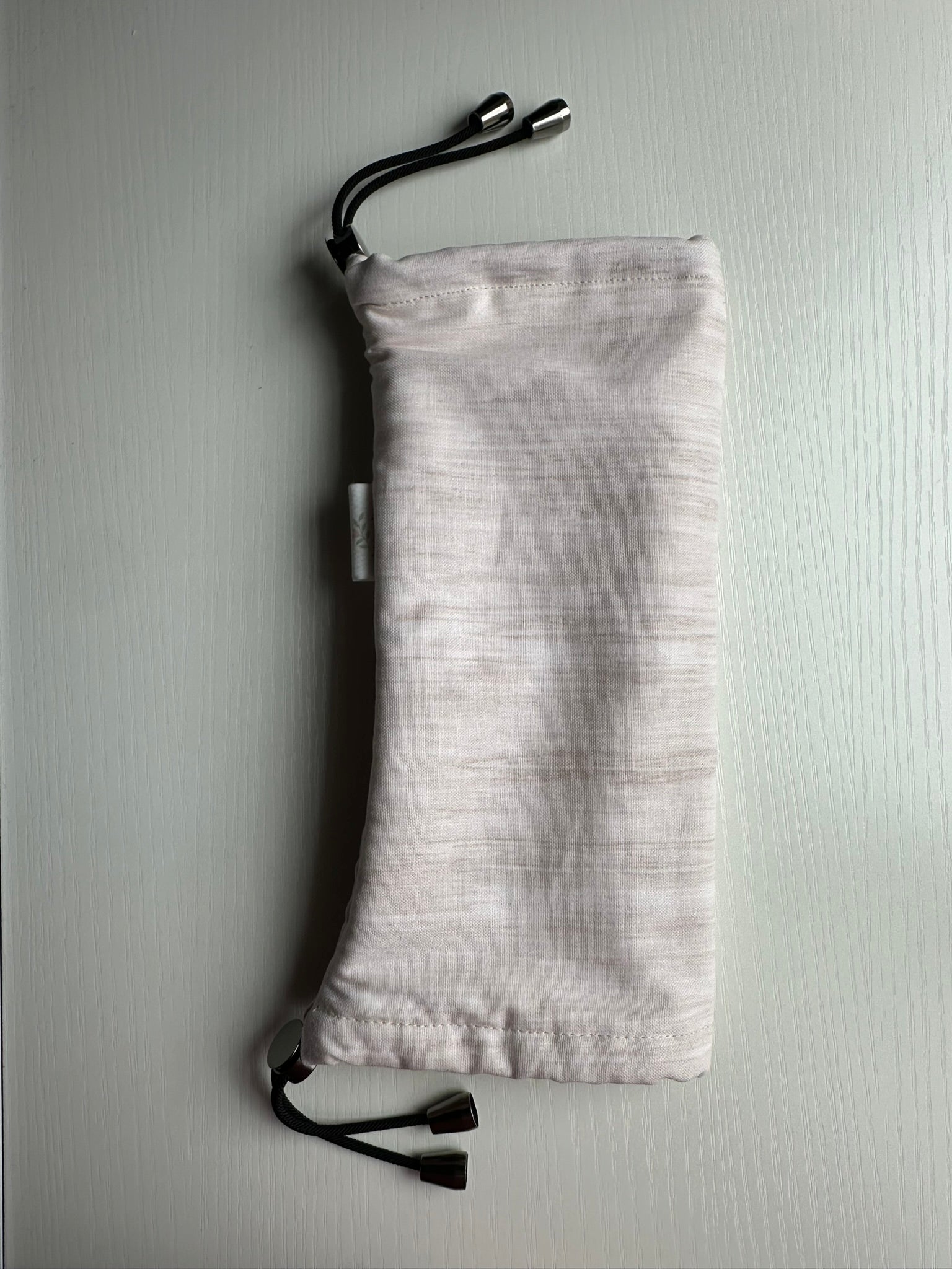 Sling Safe drawstring washing cover for ring slings, shown in the pattern Sandstone. Sandstone is a beige heather. 